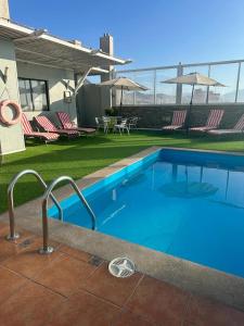 uma grande piscina azul num quintal com cadeiras em Hotel Florencia Suites & Apartments em Antofagasta