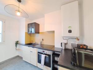 une cuisine avec des placards blancs et un comptoir noir dans l'établissement Appartement cosy au coeur de Reims, à Reims