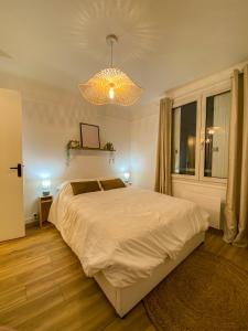 - une chambre avec un grand lit blanc et un lustre dans l'établissement Appartement cosy au coeur de Reims, à Reims