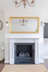 a living room with a fireplace with a mirror above it at Elegant 3 Bed Flat in Marylebone, London in London