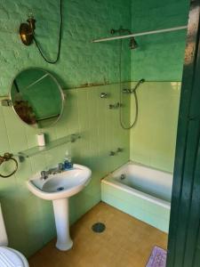 La salle de bains est pourvue d'un lavabo, d'un miroir et d'une baignoire. dans l'établissement Sitio Ramalhete - Sua escapada perfeita na Serra da Mantiqueira, à São Bento do Sapucaí