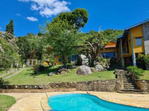 a house with a swimming pool in a yard at Sitio Ramalhete - Sua escapada perfeita na Serra da Mantiqueira in São Bento do Sapucaí