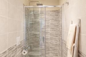 La salle de bains est pourvue d'une douche avec une porte en verre. dans l'établissement White Attic Lucca, à Lucques