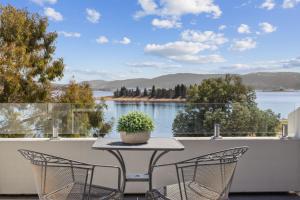 a table and chairs on a balcony with a view of the water at Horizons 404 in Jindabyne