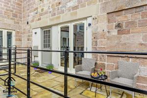 einen Balkon mit 2 Stühlen und einem Tisch mit Obst darauf in der Unterkunft Character filled Courtyard Escape in Harrogate