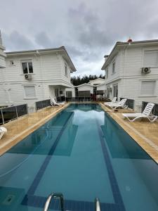 a large swimming pool with chairs and a house at Royal Villa in Forest in Dosemealti