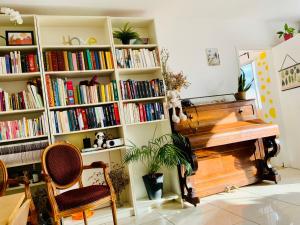 a book shelf filled with books next to a piano at Une chambre chez moi,A guest room in my home,20mins to Paris in Colombes