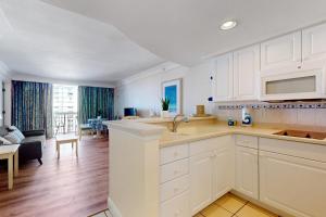 a kitchen with white cabinets and a living room at Daytona Beach Resort 1216 in Daytona Beach