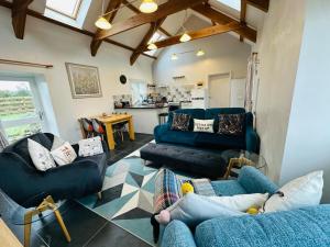 sala de estar con 2 sofás azules y cocina en Trefechan Wen Barn, en Llanwnda