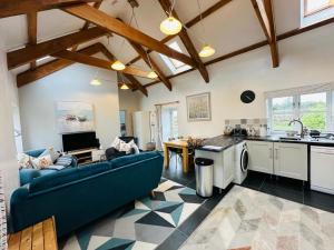 Una sala de estar con un sofá azul y una cocina. en Trefechan Wen Barn, en Llanwnda