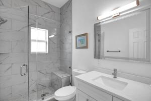 a white bathroom with a toilet and a sink at Carney's Reef NEW 1B 1B Pool Patio in Marathon
