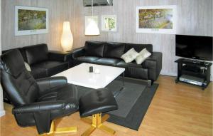 SpodsbjergにあるCozy Home In Rudkbing With Wifiのリビングルーム(黒革の家具、白いテーブル付)