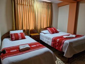 Habitación de hotel con 2 camas con sábanas rojas y blancas en Hotel Colquewasi, en Cusco