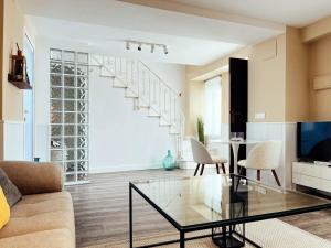 a living room with a glass coffee table and a staircase at María Luisa Home in Priego de Córdoba