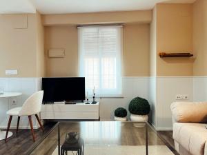 uma sala de estar com uma televisão e um sofá em María Luisa Home em Priego de Córdoba
