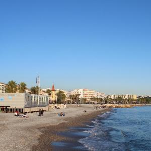 a beach with people on the sand and the water at Coquet logement front de mer in Cagnes-sur-Mer