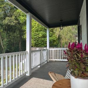 a porch with a white fence and a table with purple flowers at Bespoke 1920's Charm, Walk 2 Warren, & Hot Tub - The Spring House in Hudson