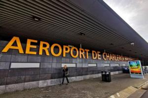 un homme marchant devant un panneau sur un bâtiment dans l'établissement Charleville 39 H Bruxelles-charleroi-aéroport, à Charleroi