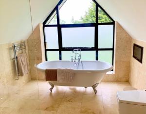 uma grande casa de banho com banheira e uma grande janela em Luxury 5 Bed all en-suite home with Hot tub em Hale