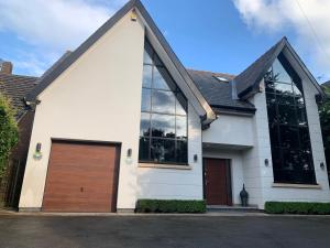 a white house with a wooden garage door at Luxury 5 Bed all en-suite home with Hot tub in Hale