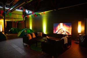 a living room with a couch and a tv on a wall at Indoor Camping Helsinki in Helsinki