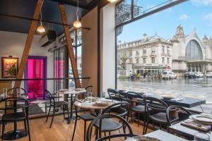 a restaurant with tables and chairs and a view of a street at LABE Hôtel Tours Centre Gare in Tours