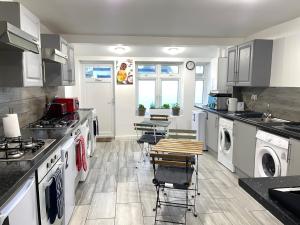 una cocina con electrodomésticos blancos, mesas y sillas en Rom Gardens - Comfortable & Spacious 2 Bedroom Apartment - 2 en Friern Barnet