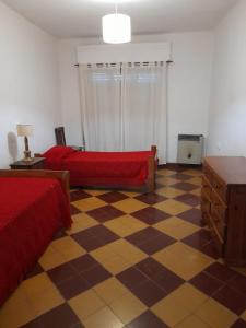 a bedroom with a red bed and a checkered floor at Casa Quinta Estilo Campo in Lobos +19 photos