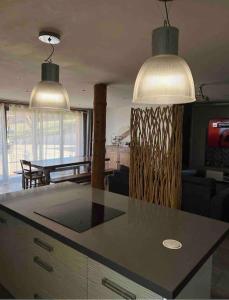 une cuisine avec deux lampes suspendues et une table dans l'établissement Ma maison en bois avec Jacuzzi, à Lavelanet