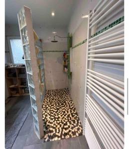 um quarto com um chuveiro com uma porta e um piso com cogumelos em Ma maison en bois avec Jacuzzi em Lavelanet