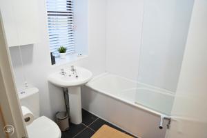a bathroom with a sink and a tub and a toilet at Portrush by the Sea - 2 Dunluce Green in Portrush