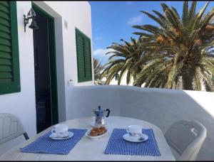 una mesa blanca con servilletas azules y una tetera en ella en Lido Playa Apartamento, en Cotillo