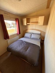 a small bedroom with a bed in a caravan at 3 bedroom pet friendly Lyons Winkups Towyn in Abergele