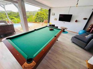 a living room with a pool table and a tv at Villa Parataito- Le Paradis entre Terre et Mer in Mahina