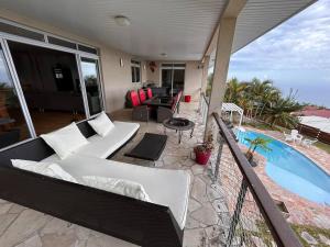 a balcony with a white couch and a pool at Villa Parataito- Le Paradis entre Terre et Mer in Mahina