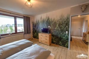 1 dormitorio con un gran mural de árboles en la pared en Auszeit-im-Harz Haus 3 Wohnung 5, en Braunlage