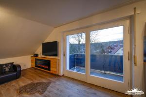 een woonkamer met een groot raam en een open haard bij Auszeit-im-Harz Haus 3 Wohnung 8 in Braunlage