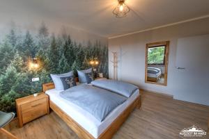 - une chambre avec un lit orné d'une peinture d'arbres dans l'établissement Auszeit-im-Harz Haus 3 Wohnung 4, à Braunlage