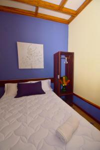 1 dormitorio con 1 cama blanca grande y pared azul en HOTEL LA RIVIERA, en Sabalito