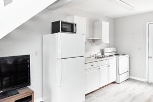 a white kitchen with a refrigerator and a tv at Sunset Villa in Chincoteague