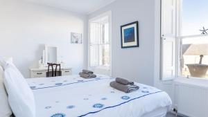 a white bedroom with a bed with towels on it at Susie's Place in Elie