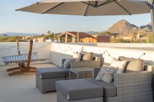 a patio with several couches and an umbrella at Golf Sim & Putting Green - Rooftop with 360 Views in Scottsdale
