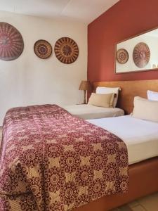 two beds in a hotel room with red walls at Hotel Le Marly in Abidjan