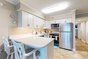 a kitchen with white cabinets and a stainless steel refrigerator at Marigot Beach 1205 in Ocean City