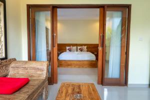 a bedroom with a bed and a glass door at Pondok Aruna in Ubud