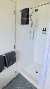 a white bathroom with a shower with black towels at Lake Dunstan Motel in Cromwell