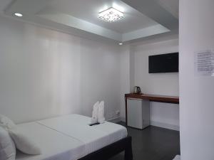 a white room with a bed and a television at MGG CASA DELA PLAYA in Boracay