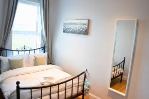 a bedroom with a bed and a mirror at Portrush by the Sea - 3 West Beach in Portrush