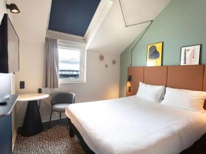 een hotelkamer met een bed, een bureau en een raam bij ibis Granville Port De Plaisance in Granville