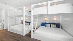 two bunk beds in a white room with wood floors at Shaker of Salt in Siesta Key